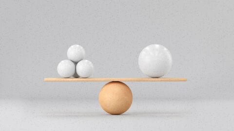 A tan ball acts as a fulcrum balancing a board that has three balls on one side and one larger ball on the other side, representing balance and simplicity.