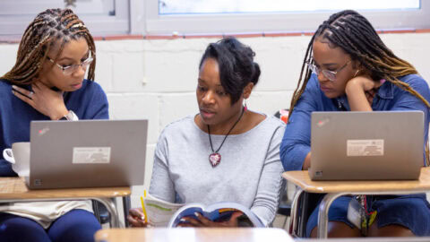 Three young women sitting at desks with laptops.