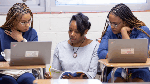 Three young women sitting at desks with laptops.