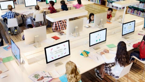 a room of students taking tests on computers.