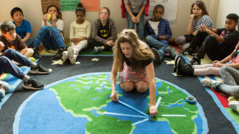 A class of students sitting in a semi-circle. One student is in the center.