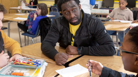A teacher works with two students at a table.